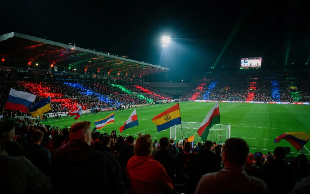 世界杯比赛夜景，球迷挥舞国旗与灯光的看台氛围图